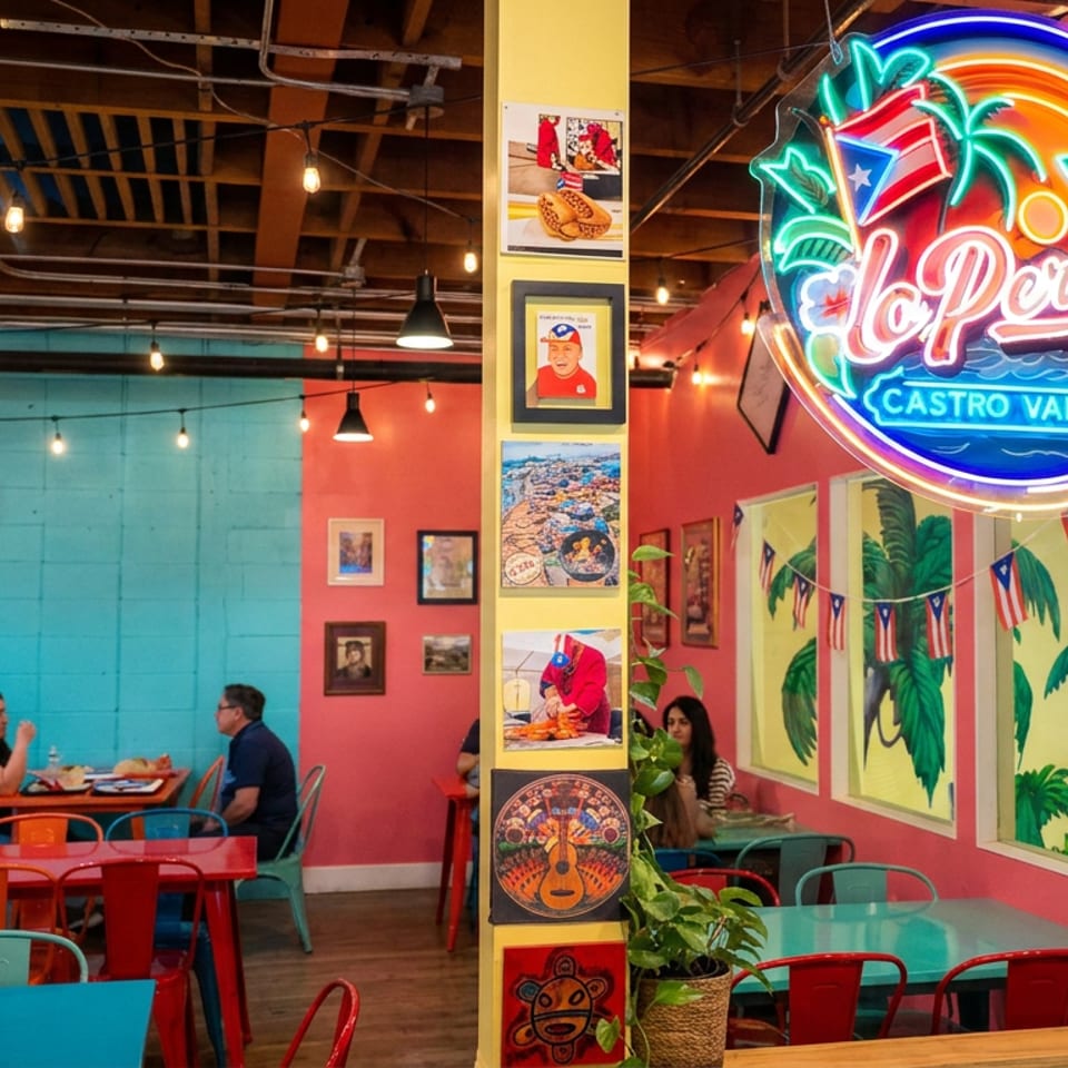 Colorful El Pollo Castro Valley restaurant interior with neon sign, tropical murals, string lights, and diners at tables.