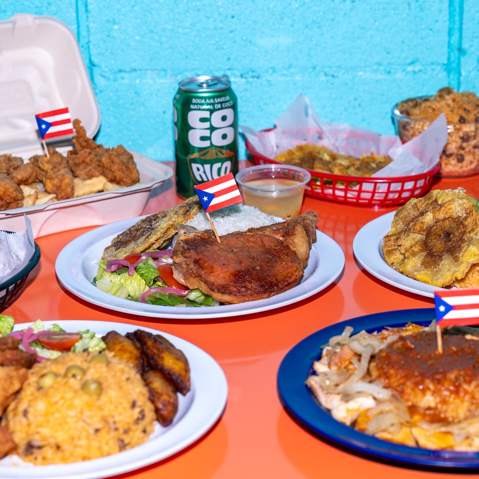Assortment of Puerto Rican dishes, including fried meats, rice, plantains, beans, and salads, displayed on colorful plates with flags.